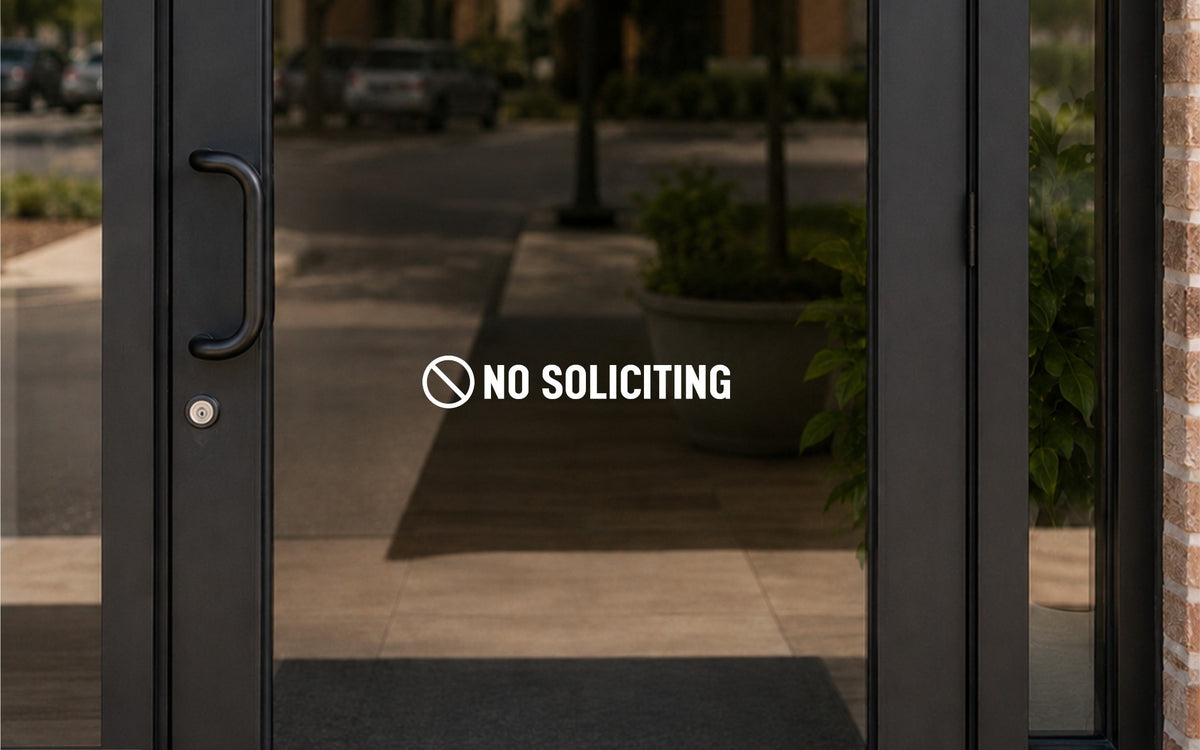 White NO SOLICITING lettering with a circle-slash symbol on a glass entry door