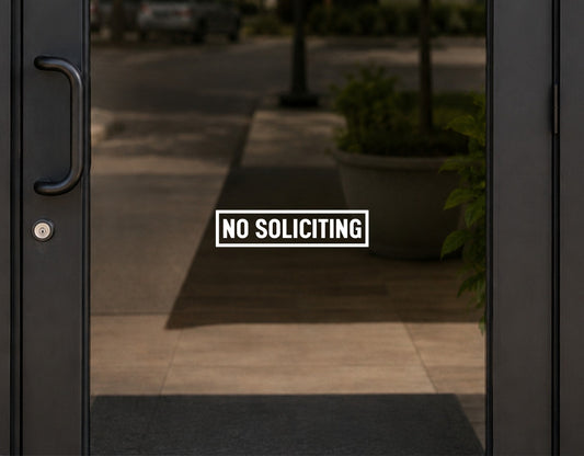White NO SOLICITING lettering and rectangular border displayed on a glass entry door