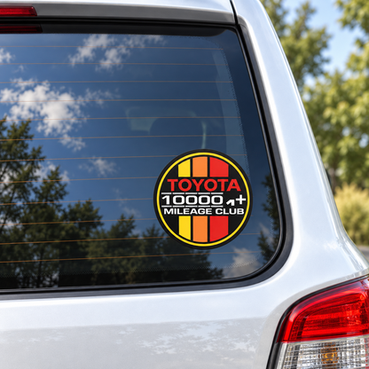 Toyota 100,000+ Mileage Club sticker with yellow, orange and red stripes shown on a vehicle rear window.